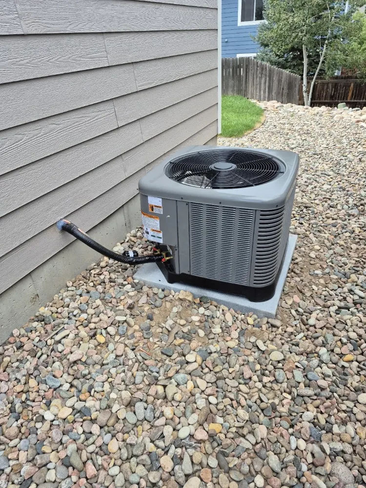 Rheem condenser set on a level pad over rock